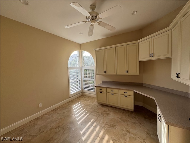 unfurnished office featuring built in desk and ceiling fan