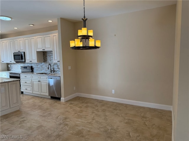 kitchen with sink, stainless steel appliances, light stone countertops, decorative backsplash, and decorative light fixtures