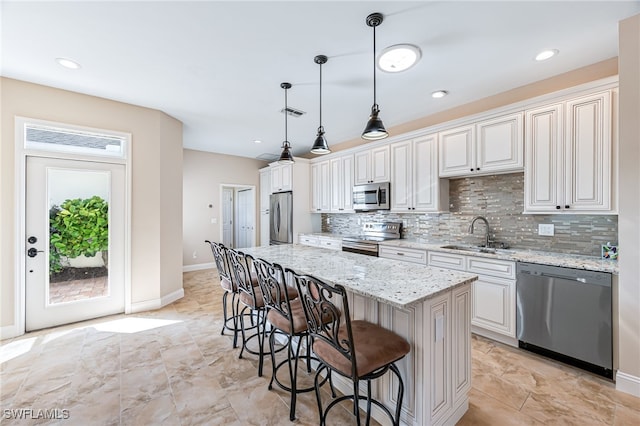 kitchen with appliances with stainless steel finishes, pendant lighting, sink, white cabinets, and a center island