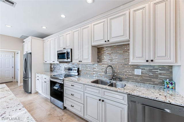 kitchen featuring stainless steel appliances, light stone countertops, and sink