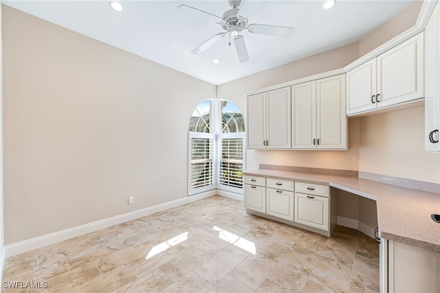 kitchen with ceiling fan, built in desk, and white cabinets