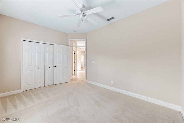 unfurnished bedroom featuring ceiling fan, light colored carpet, and a closet