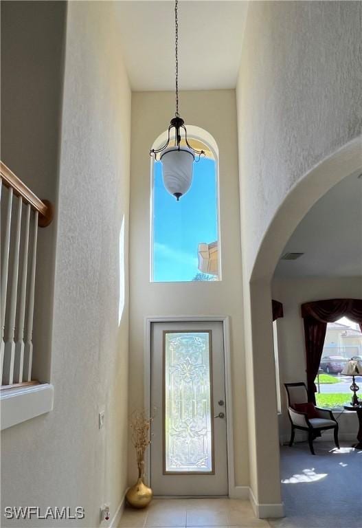 doorway to outside featuring light tile patterned floors and a towering ceiling