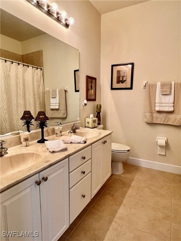 bathroom with toilet, vanity, and tile patterned flooring