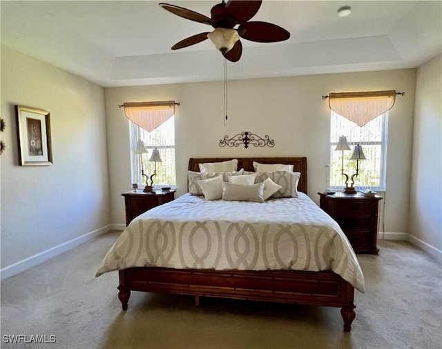 bedroom featuring ceiling fan, a tray ceiling, and carpet floors