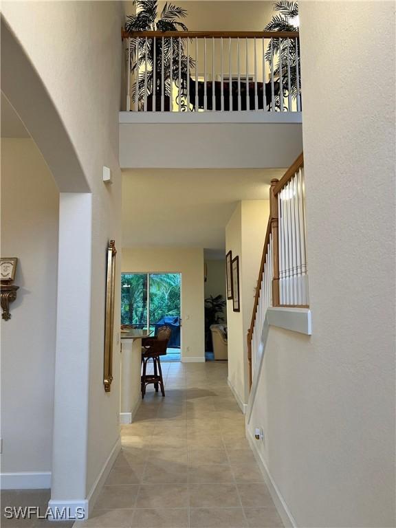 hallway with light tile patterned floors and a high ceiling