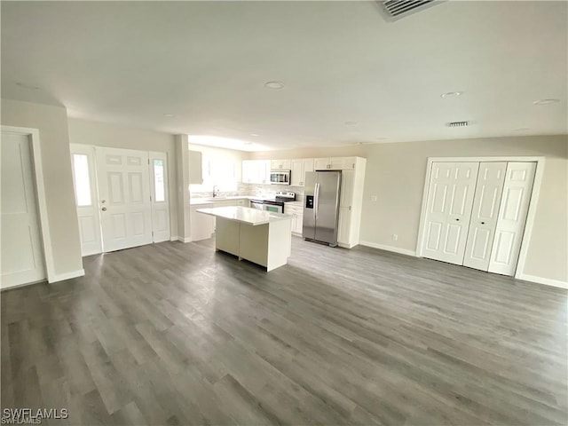 kitchen with white cabinetry, decorative backsplash, a kitchen island, dark hardwood / wood-style flooring, and stainless steel appliances