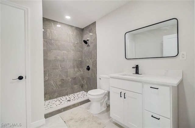 bathroom featuring tiled shower, toilet, and vanity