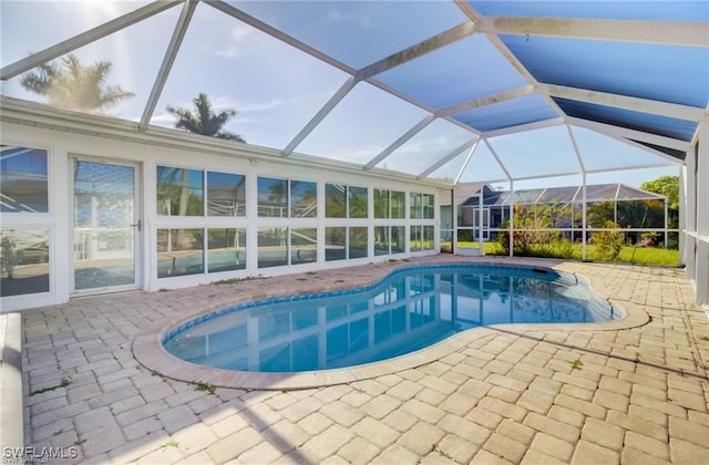 view of pool with glass enclosure and a patio