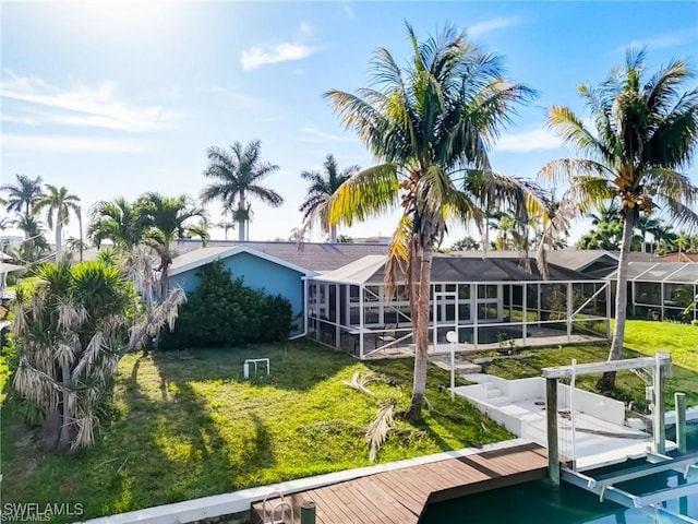 rear view of house with a lanai and a lawn