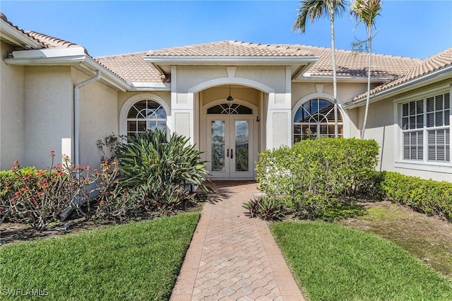 property entrance with french doors, a tile roof, and stucco siding