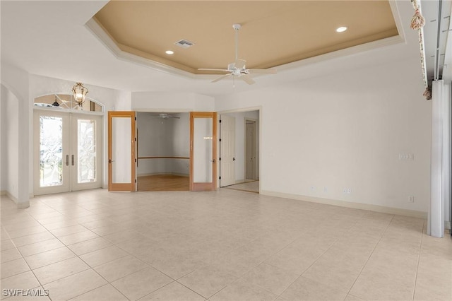 spare room with visible vents, a tray ceiling, ceiling fan, and french doors