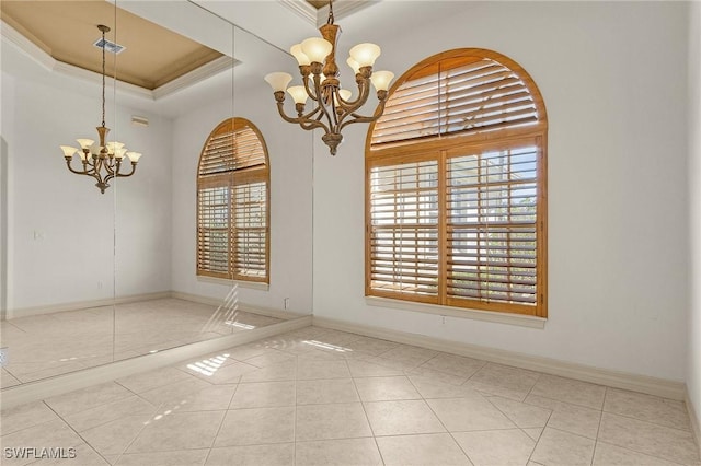 spare room featuring a tray ceiling, a notable chandelier, ornamental molding, baseboards, and tile patterned floors