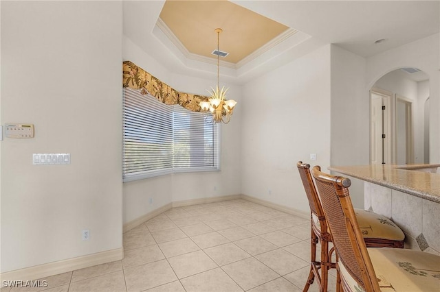 dining space with a notable chandelier, a raised ceiling, ornamental molding, light tile patterned flooring, and baseboards