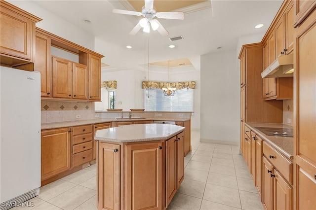 kitchen featuring under cabinet range hood, a peninsula, a kitchen island, a sink, and freestanding refrigerator