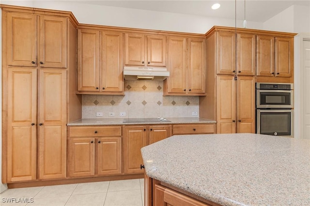 kitchen featuring under cabinet range hood, double oven, light tile patterned floors, and decorative backsplash