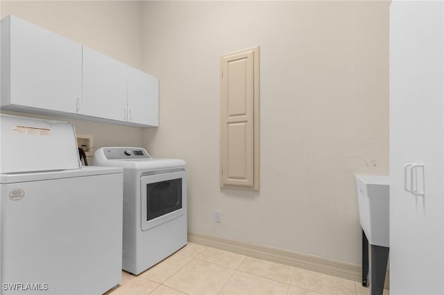 laundry area with light tile patterned floors, independent washer and dryer, cabinet space, and baseboards