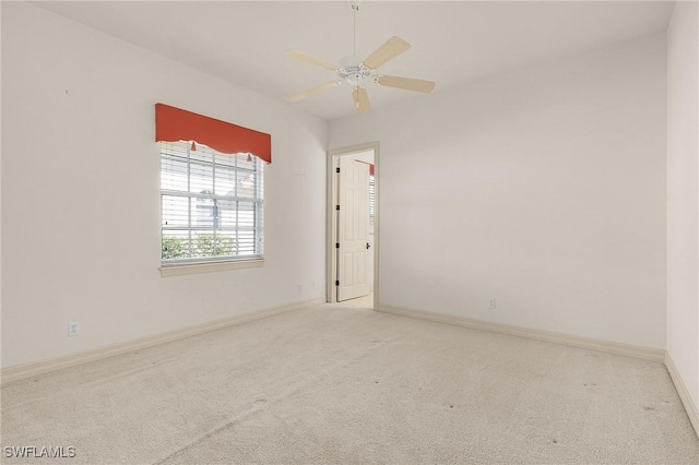 carpeted spare room featuring ceiling fan and baseboards