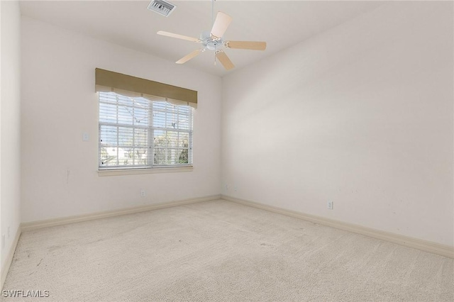 carpeted spare room featuring ceiling fan, visible vents, and baseboards