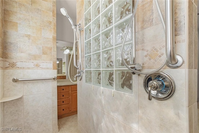 bathroom with vanity, tile patterned flooring, a tile shower, and tile walls