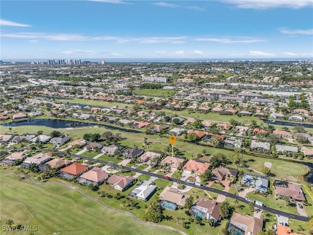 drone / aerial view with view of golf course, a water view, and a residential view