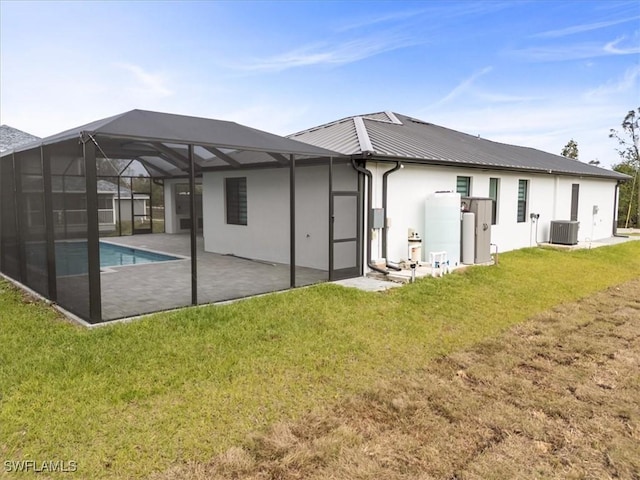 back of house with a lanai, a patio area, central AC, and a lawn