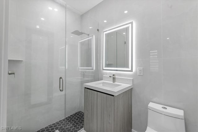 bathroom with toilet, vanity, tile walls, and walk in shower