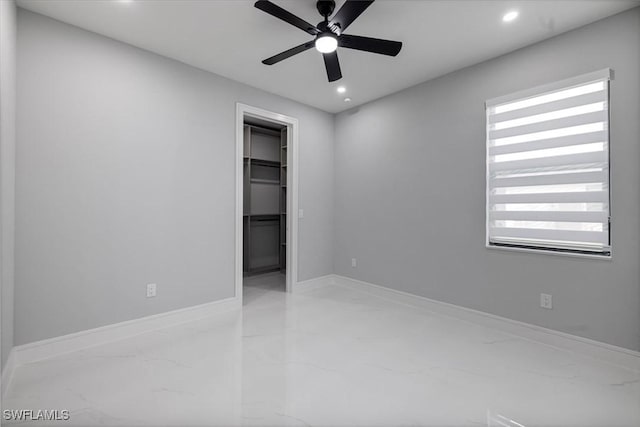 unfurnished bedroom with a spacious closet, ceiling fan, a closet, and multiple windows