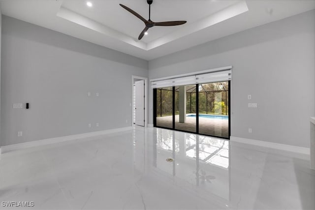 empty room featuring ceiling fan and a tray ceiling