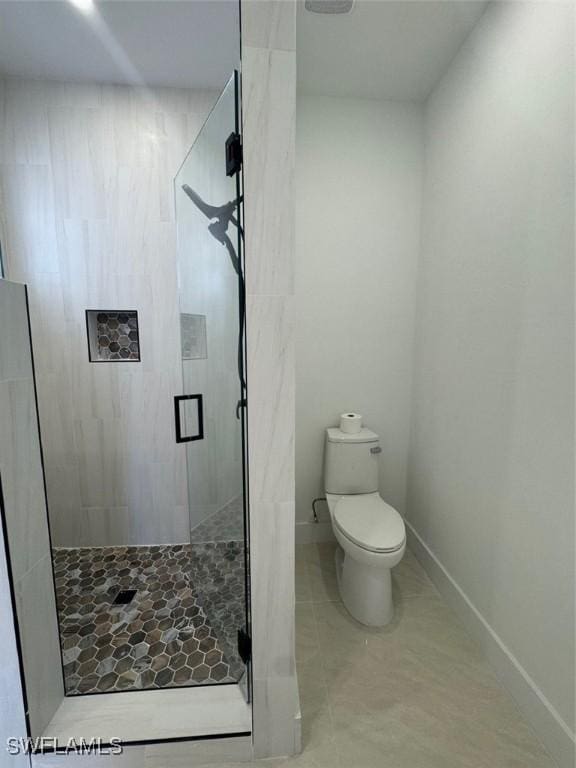 full bath featuring tile patterned flooring, baseboards, a shower stall, and toilet