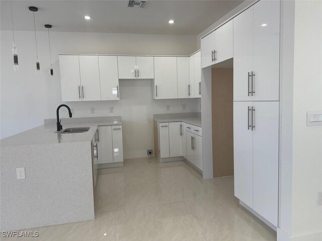 kitchen with light tile patterned floors, white cabinets, and sink