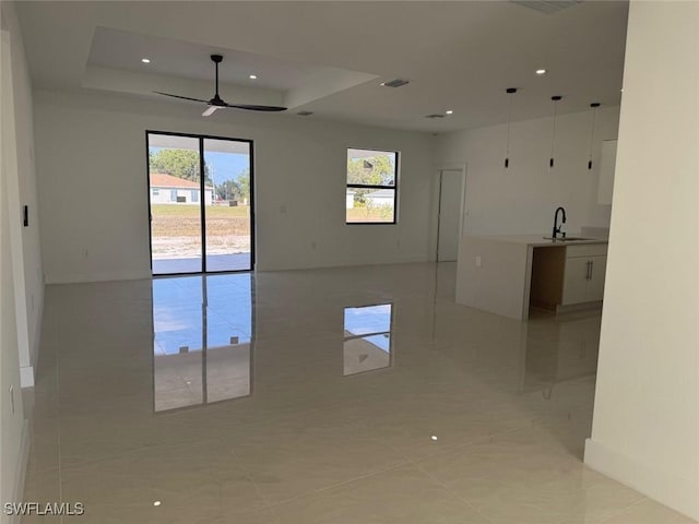 unfurnished room featuring a raised ceiling, ceiling fan, and sink