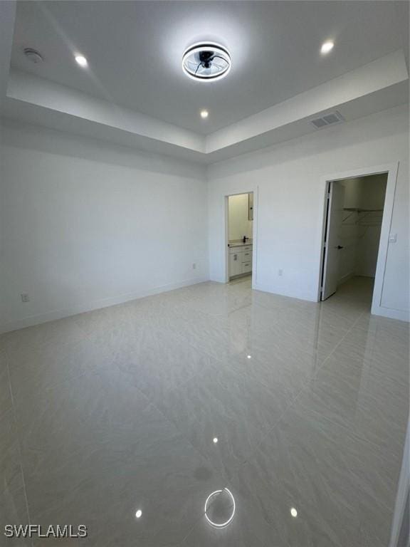 unfurnished bedroom featuring a tray ceiling, visible vents, a spacious closet, and recessed lighting