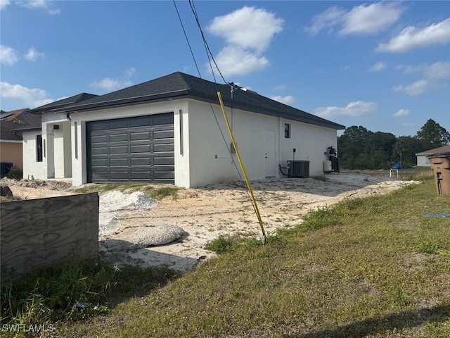 view of property exterior with a lawn, central AC, and a garage