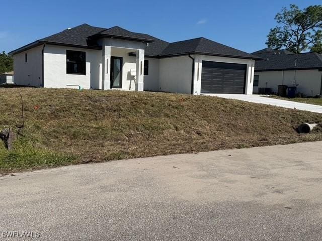 prairie-style home with a garage, concrete driveway, and stucco siding