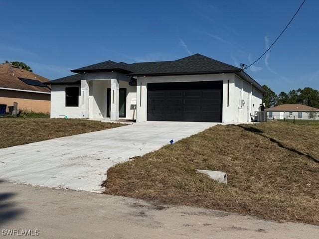 view of front of property with a garage, concrete driveway, central AC, and stucco siding