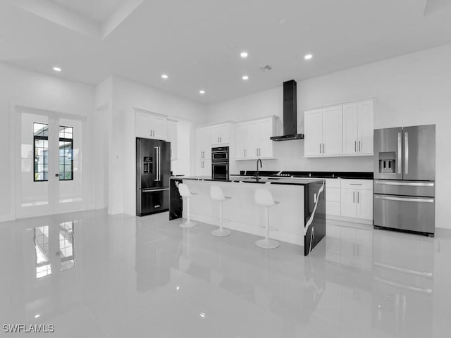 kitchen with white cabinets, wall chimney exhaust hood, stainless steel fridge, a kitchen island with sink, and high end fridge