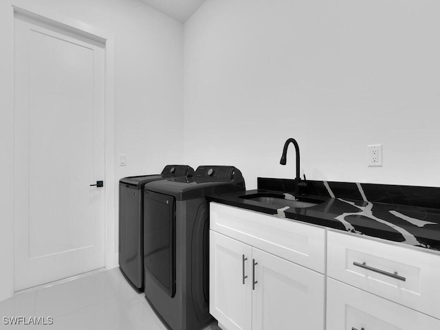 clothes washing area with light tile patterned floors, sink, separate washer and dryer, and cabinets