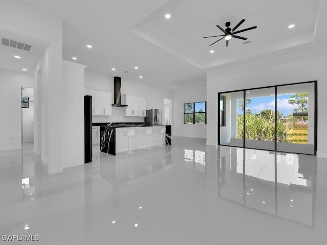 unfurnished living room with ceiling fan and a tray ceiling