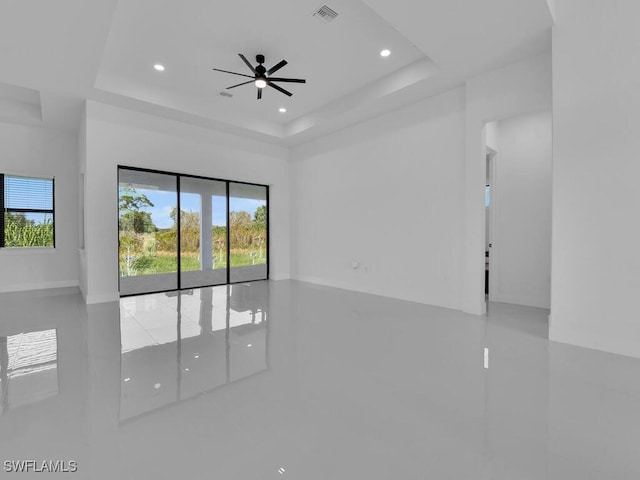 tiled spare room featuring a raised ceiling and ceiling fan