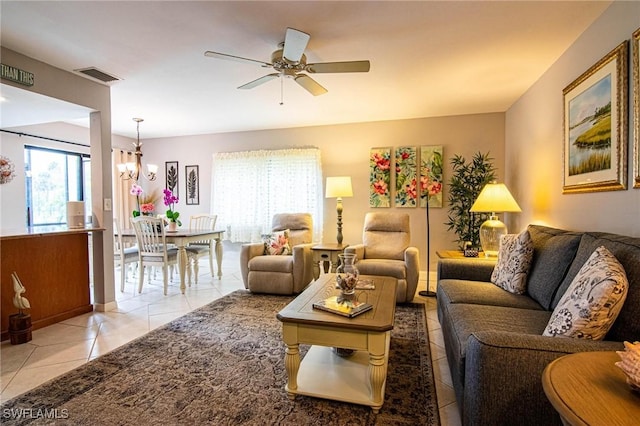 tiled living room with ceiling fan with notable chandelier