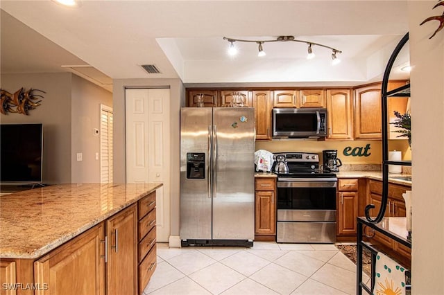 kitchen featuring light stone countertops, light tile patterned floors, and stainless steel appliances