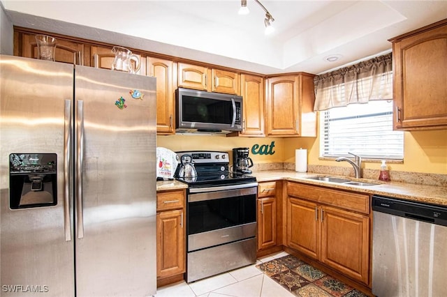 kitchen with a tray ceiling, sink, appliances with stainless steel finishes, and light tile patterned flooring