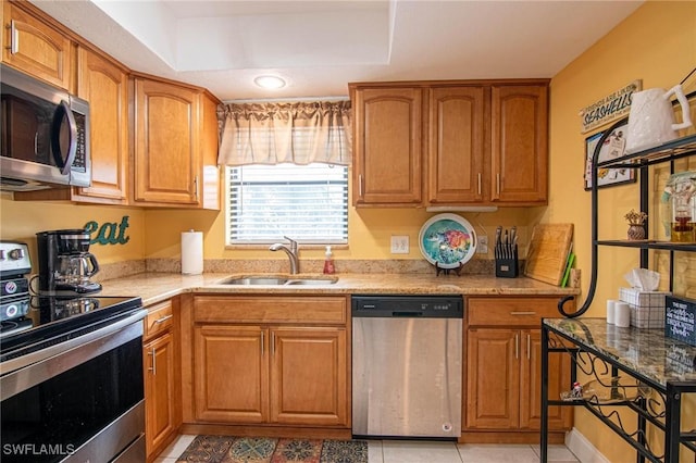 kitchen featuring light tile patterned floors, sink, light stone counters, and stainless steel appliances