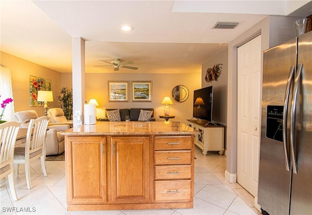 kitchen featuring stainless steel refrigerator with ice dispenser, ceiling fan, kitchen peninsula, light stone counters, and light tile patterned floors