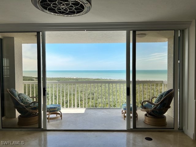 doorway to outside with a water view, concrete floors, and a view of the beach