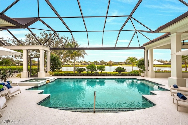 view of pool with an in ground hot tub, a patio area, glass enclosure, and a water view