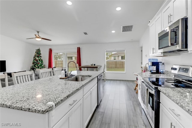 kitchen featuring stainless steel appliances, an island with sink, white cabinets, and sink