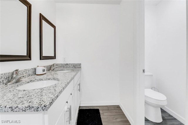 bathroom with toilet, hardwood / wood-style floors, and vanity