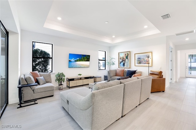 living room with light tile patterned floors, plenty of natural light, and a tray ceiling